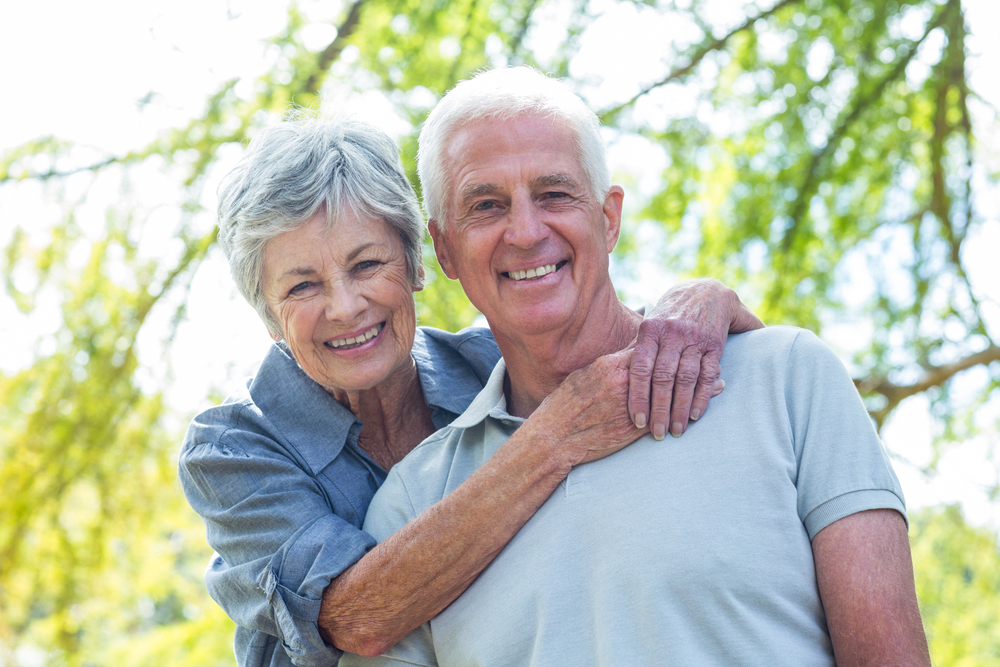 Elderly couple smiling in nature. 